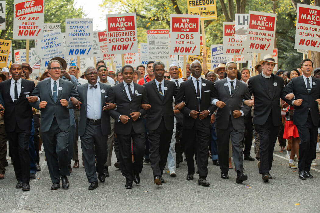 Colman Domingo and others walking in protest in suits.