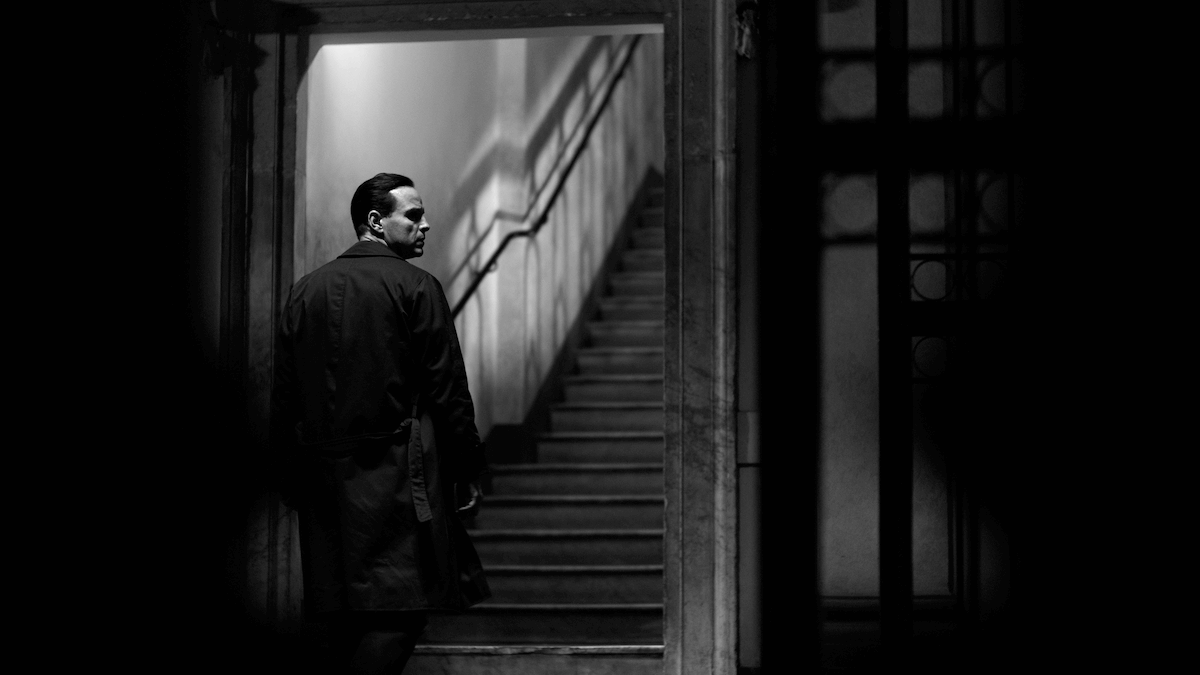 Black and white photo of Andrew Scott walking up the stairs looking over his shoulder.