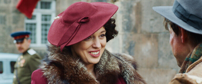 Smiling woman wearing a mink coat and a pink hat.