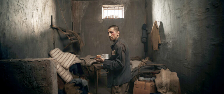 A man in a prison cell reading.