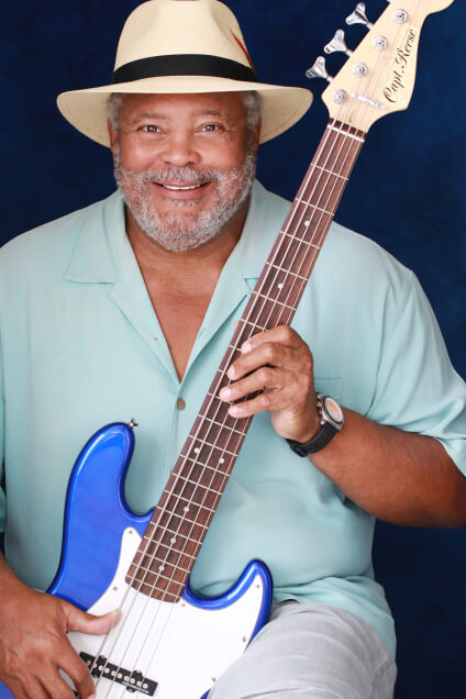 Actor Capt. Reese smiling with a blue bass guitar.