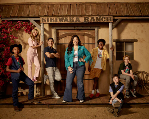 The cast of Disney's BUNK'D in front of a wooden ranch set.