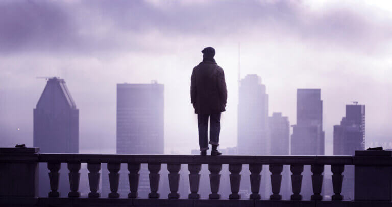 Hakim Brahimi on top of a columned banister overlooking a city in the film Montréal Girls.