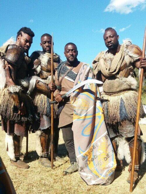 Actor Mark Willisin costume on the set of Black Panther with fellow actors.