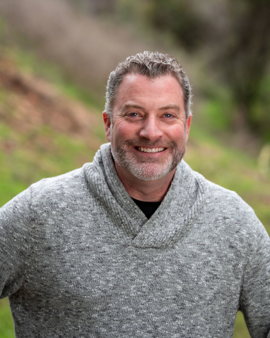 Actor Jeremy Broekman outside smiling in a grey sweater.