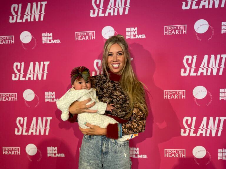 Actor Kate Lister smiling and holding her newborn baby at the premiere of SLANT.