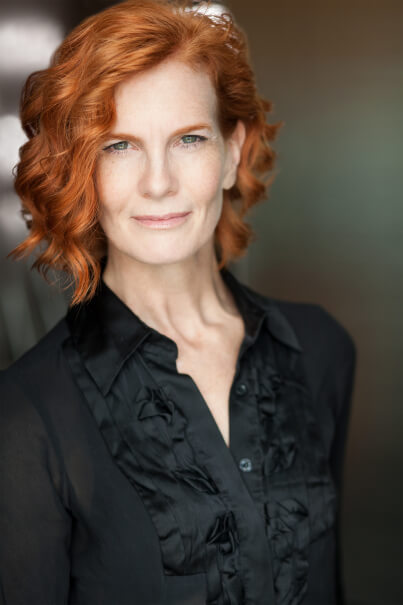 Actor Laura England in a black shirt smiling.