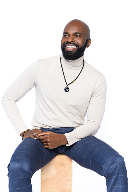 Actor Leland B Thompson smiling and looking confident while sitting on a stool.