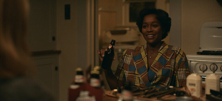 Aja Naomi King in a kitchen wearing 1950s clothing smiling.