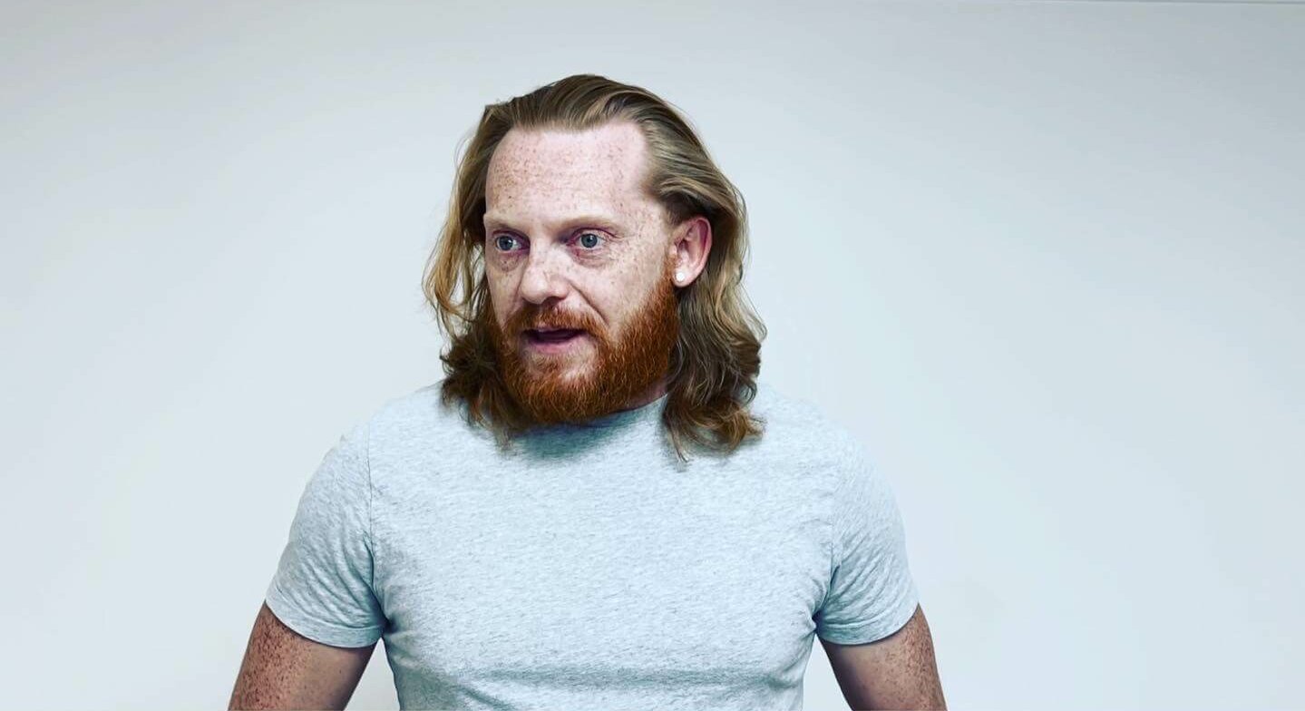 Casting Director Mathew Waters wearing a white shirt in front of a gray wall.