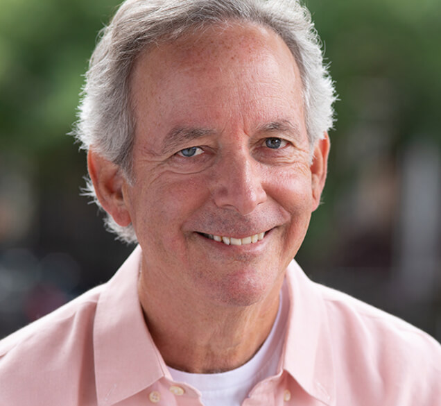 Actor Paul Murray smiling outside in a pink polo shirt.