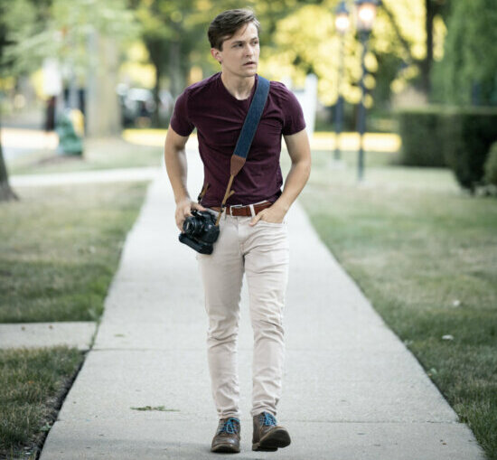 Actor Danny Irizarry walking down a suburban street in a red shirt.