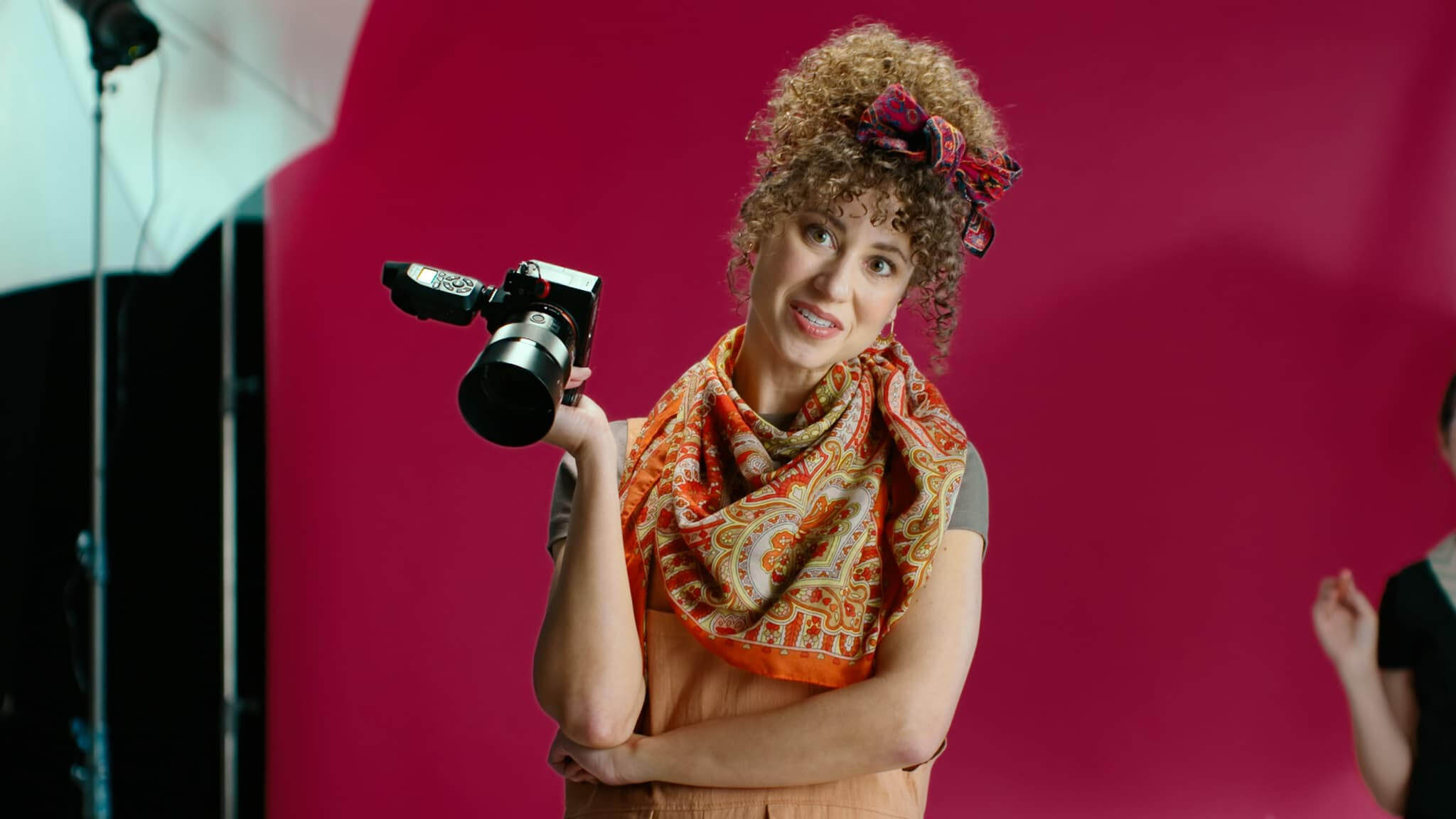 Actor Gabriella Gonzalez Biziou posing as a photographer with a camera during a photo shoot.