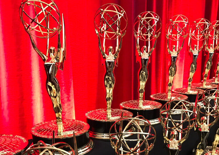 Emmy statues displayed in front of a red curtain.