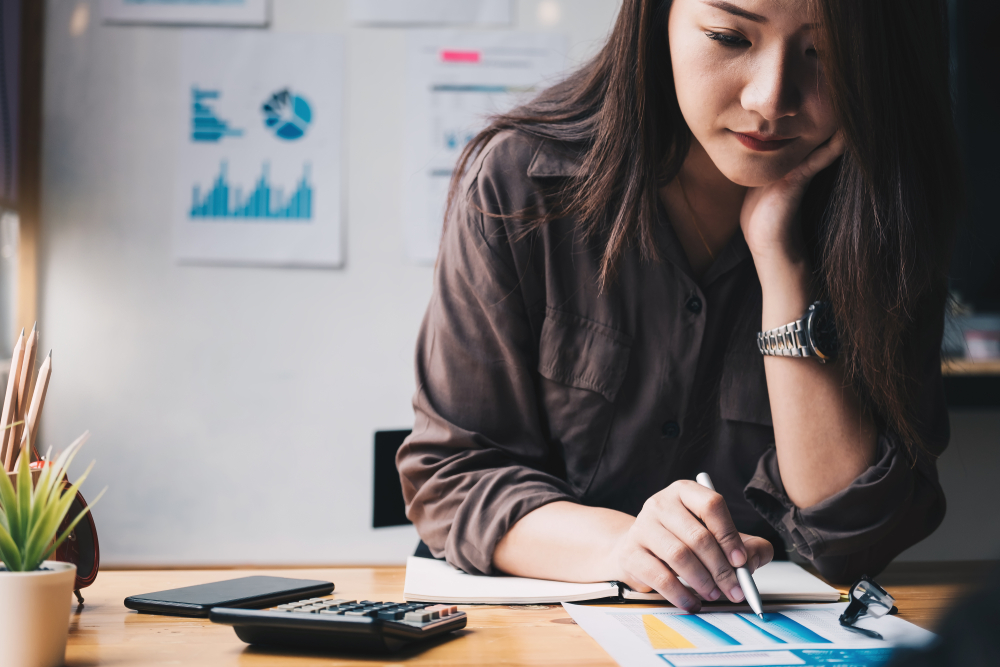 Asian woman sitting at a desk filing taxes.