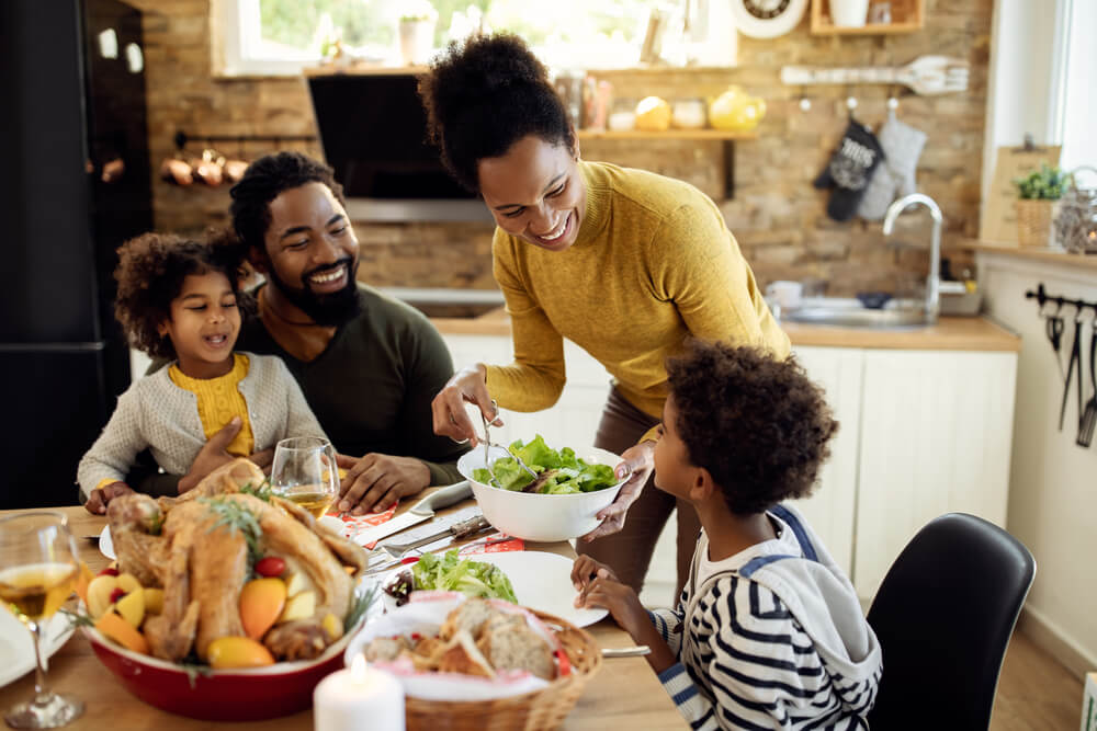 Happy African American family sitting down to a Thanksgiving dinner.