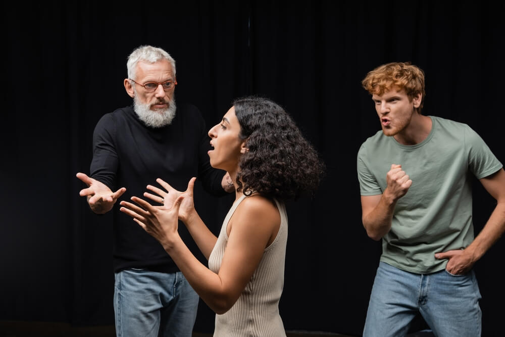 Diverse group of actors rehearsing various emotions backstage.