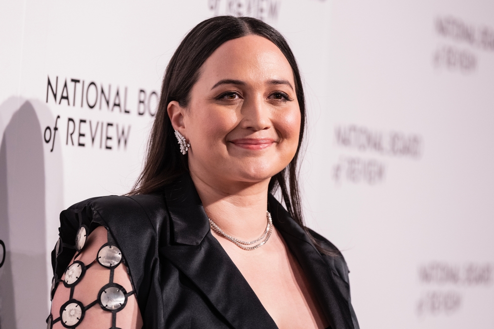 Lily Gladstone smiling in a black dress outside.