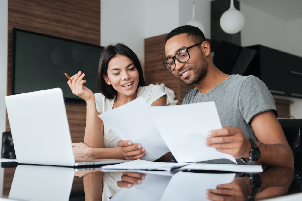 A couple at home going through finances on paper and computer.