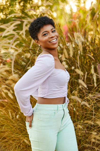 Actor Unissa Cruse standing outside a meadow smiling.