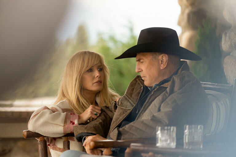 Kelly Reilly and Kevin Costner on the set of Yellowstone inside wearing old west gear.