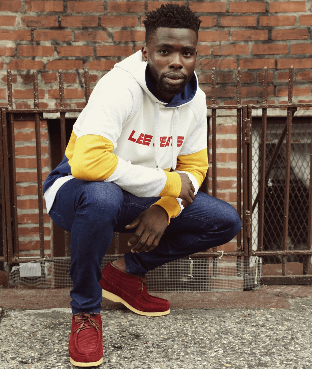 Actor and model John Adewumi outside wearing a Lee Jeans yellow and white hoodie.