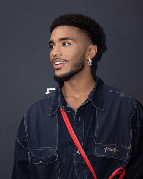 Juan Virra smiling in a denim vest.