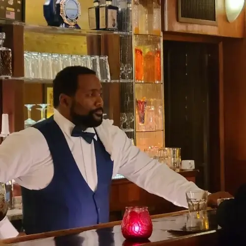 Actor Darius Cottrell tending bar in a dapper vest.